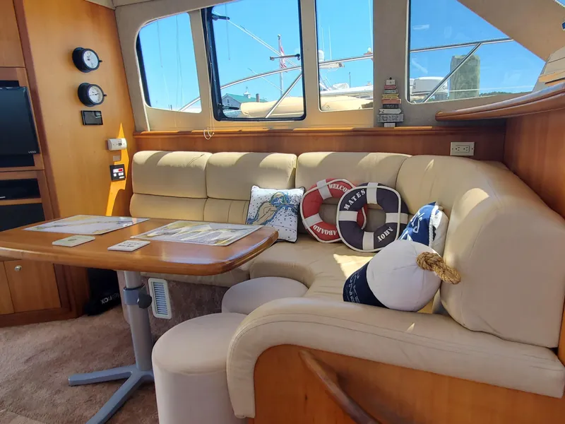 Slide: The Image of Interior of 2003 Silverton 38 Convertible yacht with cozy seating and nautical-themed pillows. - 17