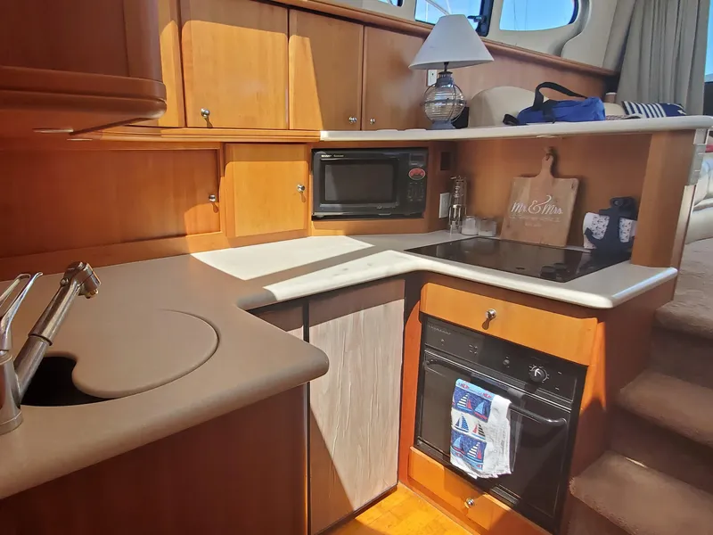 Slide: The Image of 2003 Silverton 38 Convertible yacht kitchen with wood cabinetry, stove, and microwave. - 19