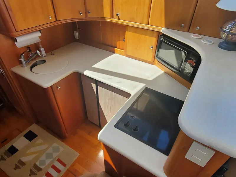 Slide: The Image of 2003 Silverton 38 Convertible yacht kitchen with wood cabinets, sink, stove, and microwave. - 20
