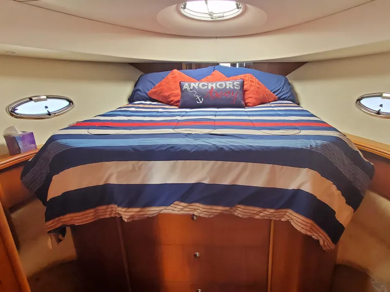 Slide: The Image of 2003 Silverton 38 Convertible cabin with striped bedding and nautical-themed pillows. - 22