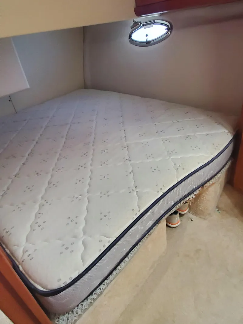 Slide: The Image of 2003 Silverton 38 Convertible boat cabin with a comfortable mattress and porthole window. - 24