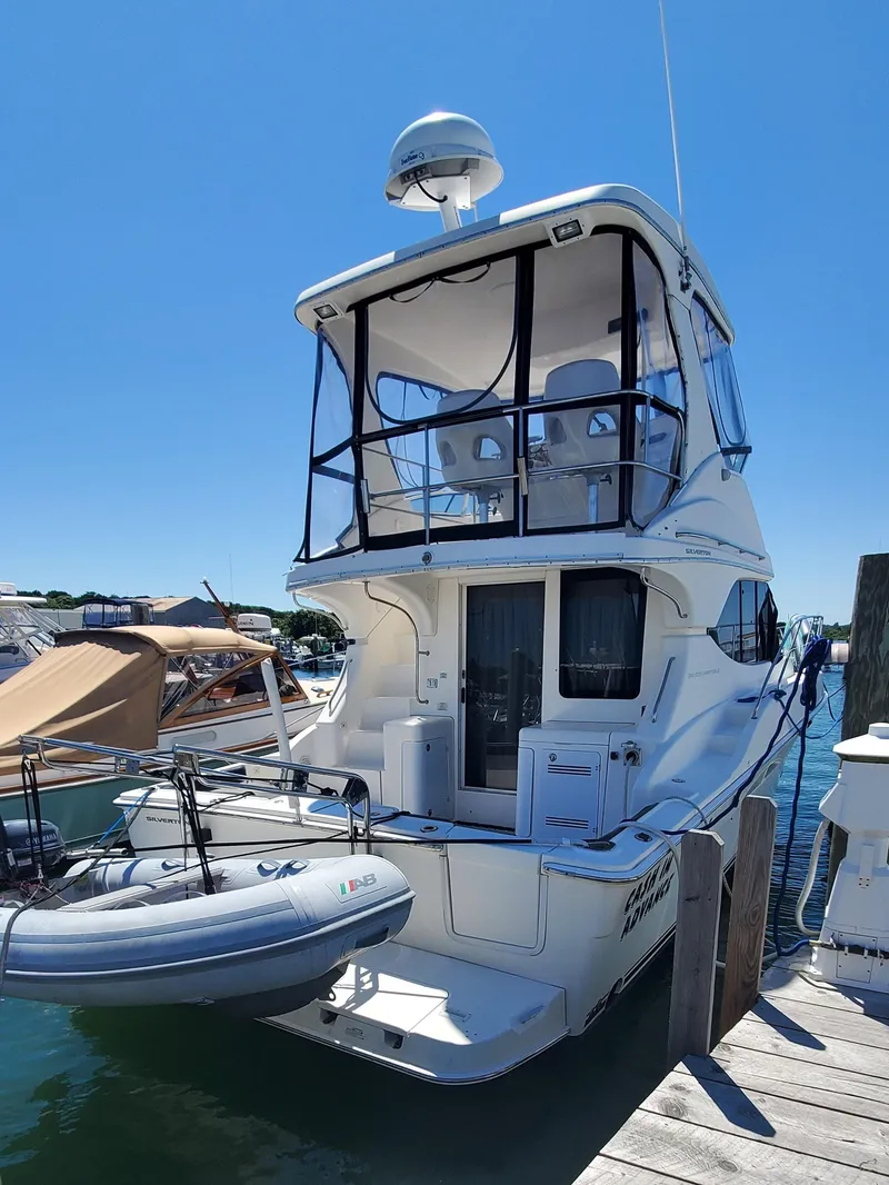 Slide: The Image of 2003 Silverton 38 Convertible yacht docked, featuring upper deck and inflatable boat. - 3