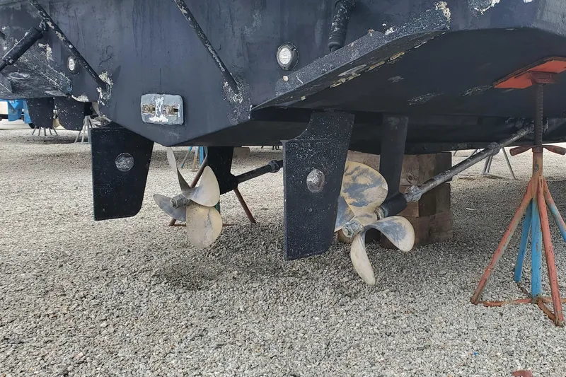 Slide: The Image of 2003 Silverton 38 Convertible boat propellers and rudders on gravel. - 31