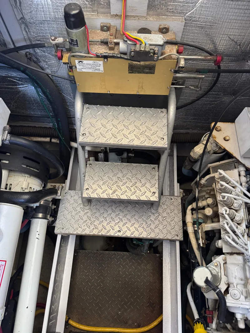 Slide: The Image of Engine room of a 2003 Silverton 38 Convertible boat, featuring metal steps and mechanical components. - 36