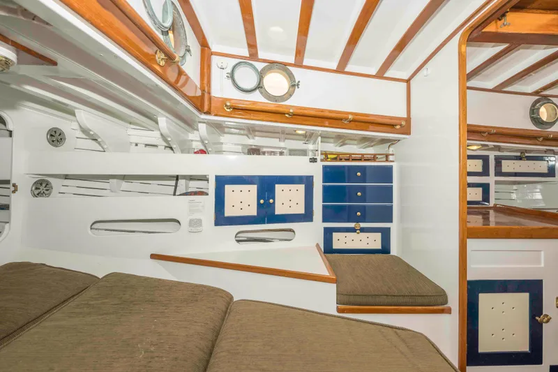 Slide: The Image of Interior of 1927 Schock Staysail Schooner with wooden beams, blue cabinets, and cozy seating. - 26