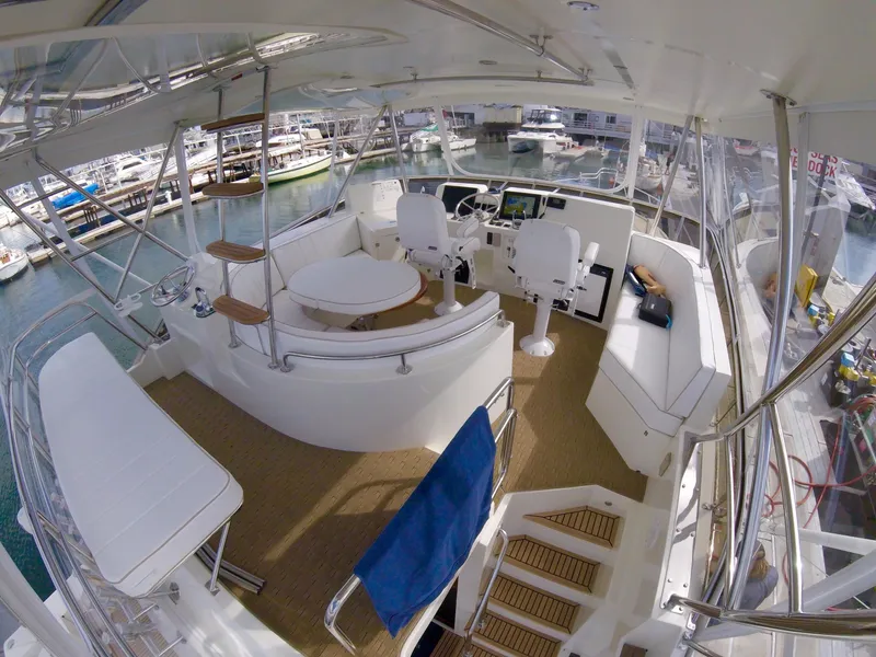 Slide: The Image of Flybridge of 2026 Mikelson 50 Generation II Sportfisher with helm, seating, and marina view. - 8