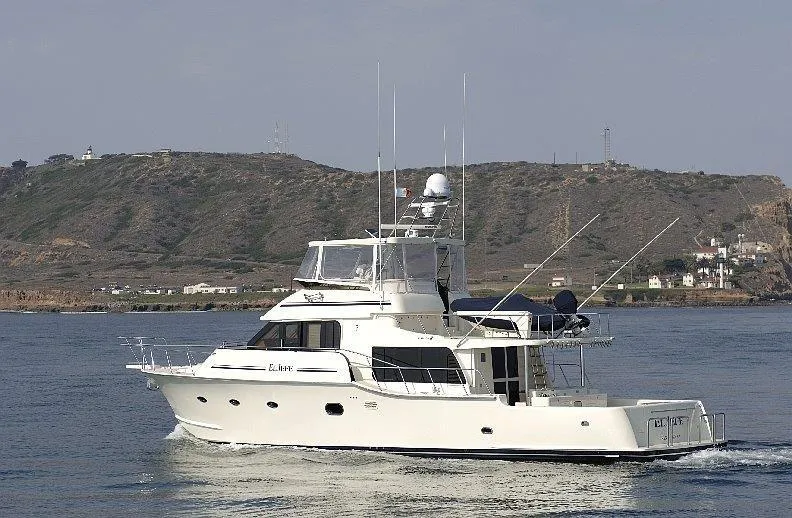 Slide: The Image of 2026 Mikelson Nomad Long Range Cruising Sportfish yacht on calm waters near a hilly coastline. - 4