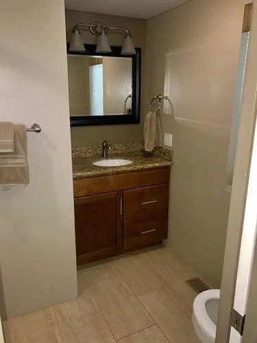 Slide: The Image of Modern bathroom with granite countertop, wooden vanity, and mirror in Bravada Why Knot Week 10, 2015. - 18