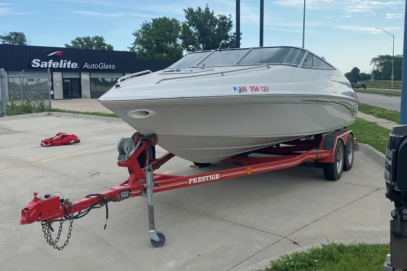 Slide: The Image of 1998 Crownline 202 CC boat on a red Prestige trailer in a parking lot. - 9