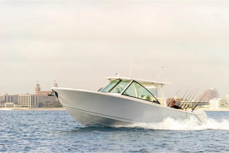 Slide: The Image of 2023 Sailfish 316 DC boat cruising on the water near a cityscape. - 2