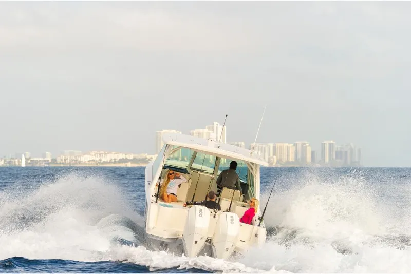 Slide: The Image of 2023 Sailfish 316 DC boat cruising on the ocean with city skyline in the background. - 26
