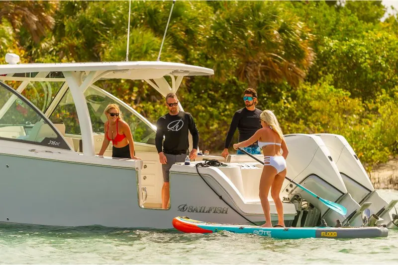 Slide: The Image of 2023 Sailfish 316 DC boat with people enjoying paddleboarding near the shore. - 34