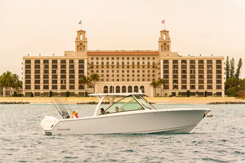 Slide: The Image of 2023 Sailfish 316 DC boat cruising near a grand waterfront hotel. - 38