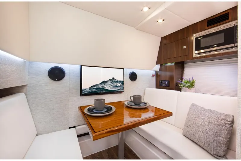 Slide: The Image of 2023 Cruisers Yachts 34 GLS I/O interior dining area with TV, microwave, and seating. - 35