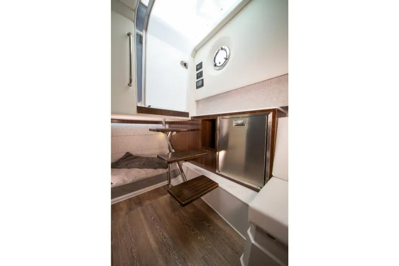 Slide: The Image of 2023 Cruisers Yachts 34 GLS I/O cabin interior with wooden flooring and compact kitchenette. - 36
