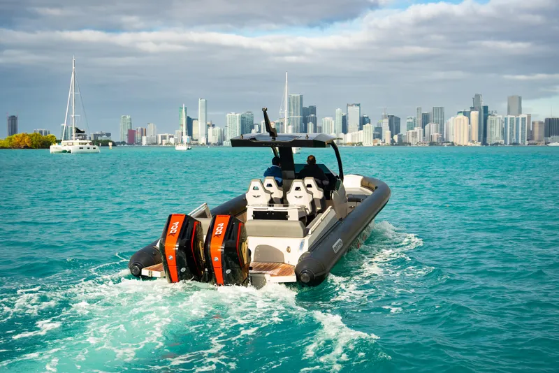Slide: The Image of 2024 Skipper-BSK 38NC boat cruising in turquoise waters with city skyline in background. - 0