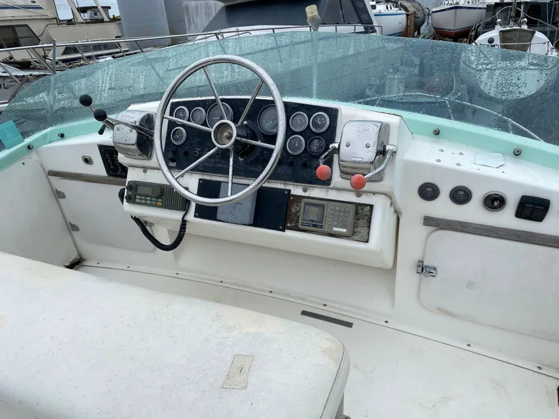 Slide: The Image of 1983 Bertram 28 FB boat cockpit with steering wheel and control panel. - 11