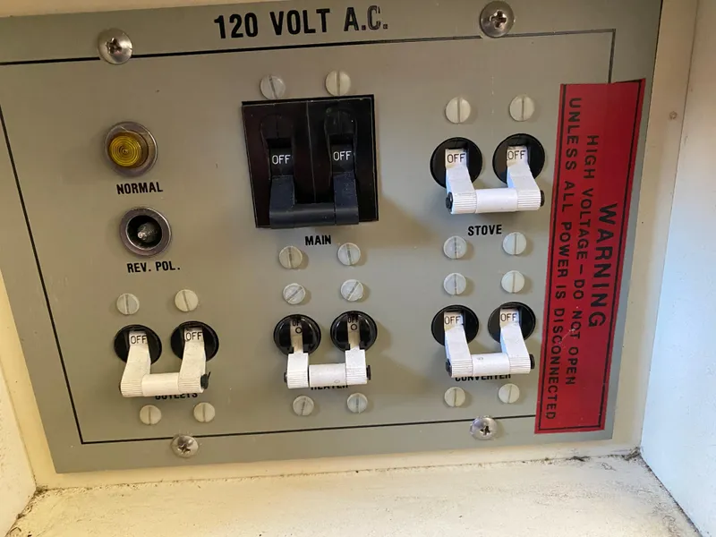Slide: The Image of 1983 Bertram 28 FB electrical panel with switches and warning label. - 16