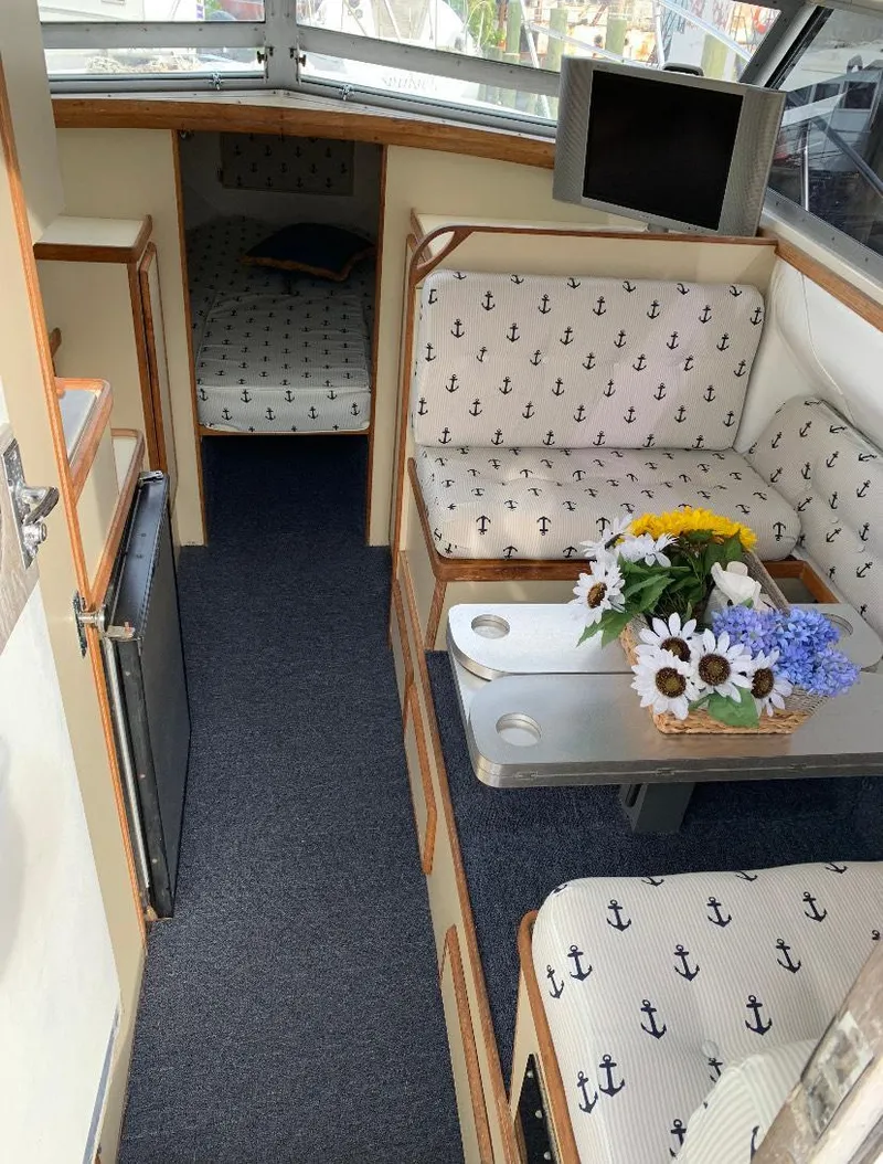 Slide: The Image of Interior of a 1983 Bertram 28 FB boat with anchor-patterned seating and floral centerpiece. - 3