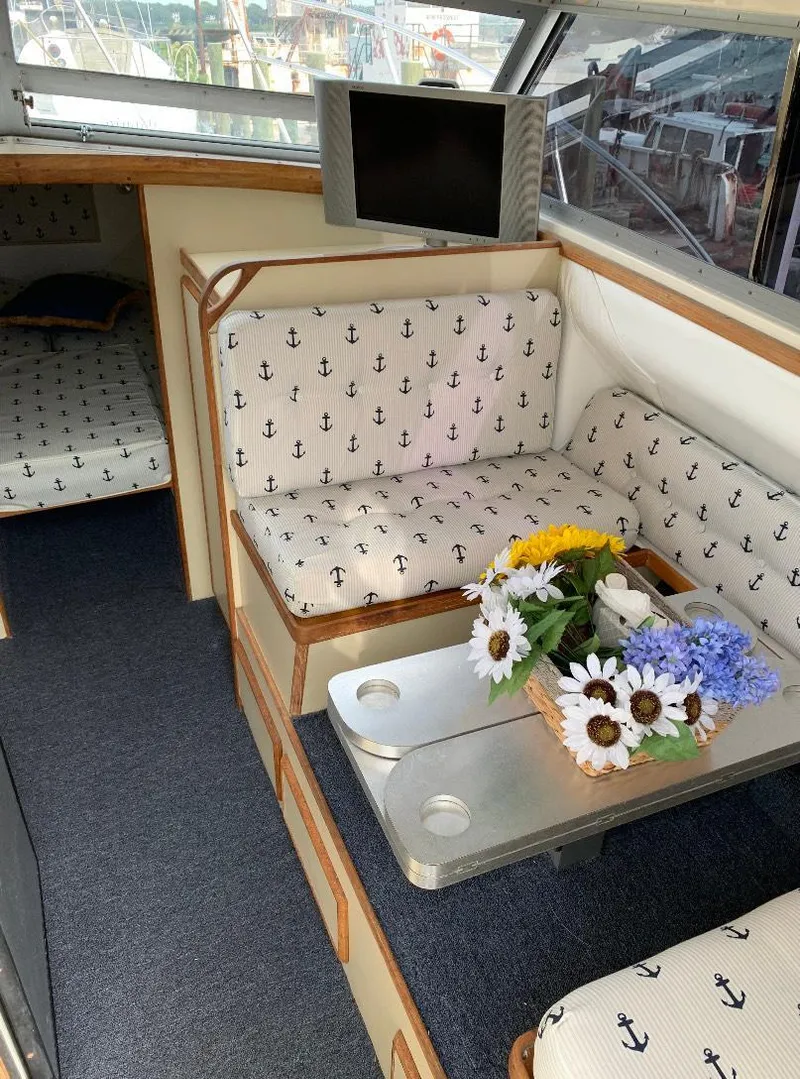 Slide: The Image of Interior of a 1983 Bertram 28 FB boat with anchor-patterned seating and floral centerpiece. - 4