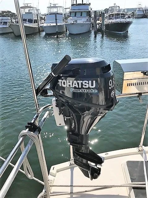 Slide: The Image of Tohatsu 9.8hp outboard motor on 1987 Tollycraft Sundecker, docked with boats in background. - 11