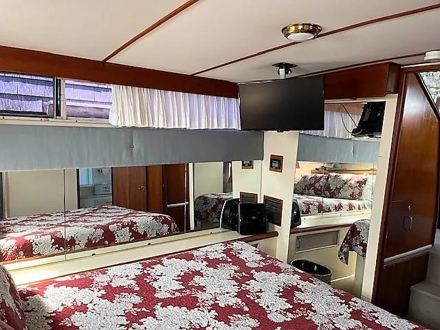 Slide: The Image of 1987 Tollycraft Sundecker Diesel bedroom with floral bedding, TV, and wood accents. - 14