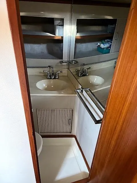 Slide: The Image of 1987 Tollycraft Sundecker Diesel yacht bathroom with sink, mirror, and storage shelves. - 17