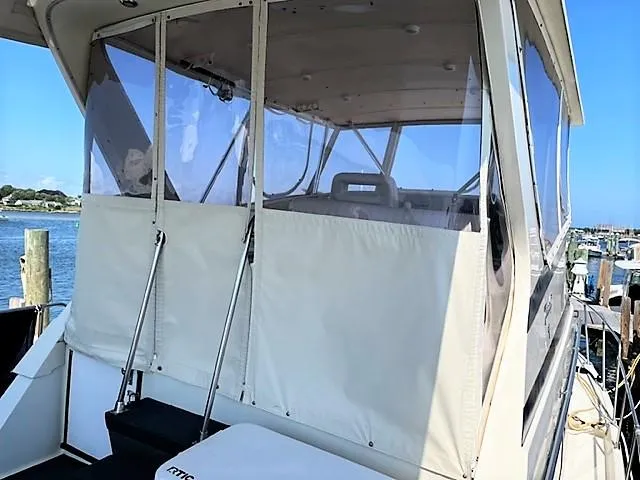 Slide: The Image of 1987 Tollycraft Sundecker Diesel boat with enclosed deck, docked by the water. - 18