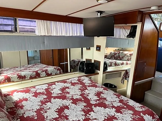 Slide: The Image of 1987 Tollycraft Sundecker Diesel bedroom with floral bedding, TV, and mirrored walls. - 20