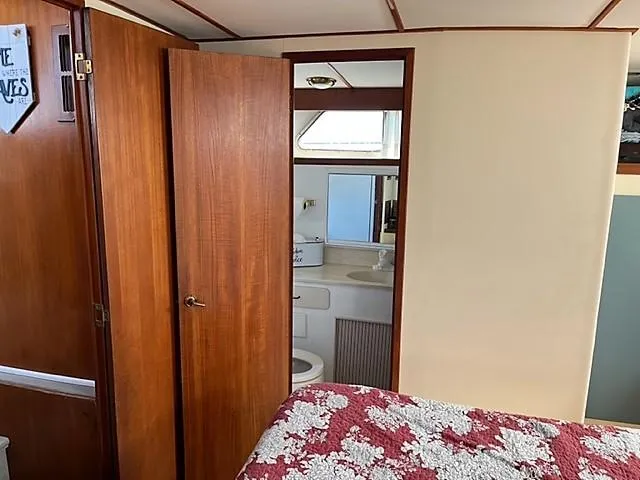 Slide: The Image of 1987 Tollycraft Sundecker Diesel interior with wooden doors, bathroom, and floral bedspread. - 21