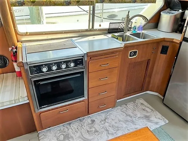 Slide: The Image of 1987 Tollycraft Sundecker Diesel yacht kitchen with stove, sink, and wooden cabinetry. - 22