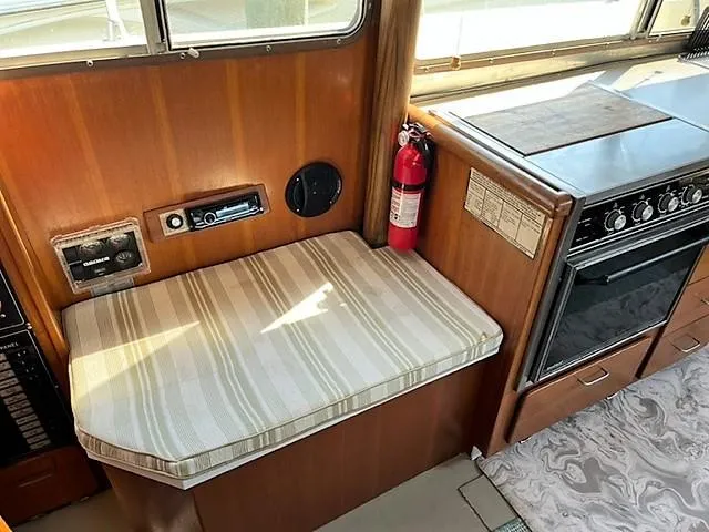 Slide: The Image of 1987 Tollycraft Sundecker interior with seating, stove, and fire extinguisher. - 23