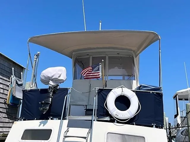 Slide: The Image of 1987 Tollycraft Sundecker Diesel boat with American flag and life preserver, docked under clear blue sky. - 27