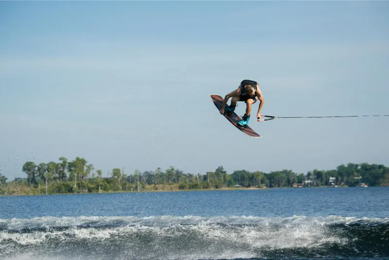 Slide: The Image of Wakeboarder performing a jump behind a 2023 Nautique Super Air GS22E boat. - 11
