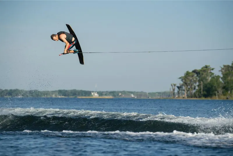 Slide: The Image of Wakeboarder performing aerial trick behind 2023 Nautique Super Air GS22E boat. - 14