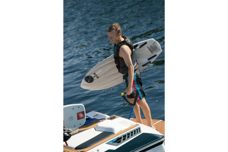 Slide: The Image of Man with surfboard on 2023 Nautique Super Air GS22E boat. - 15