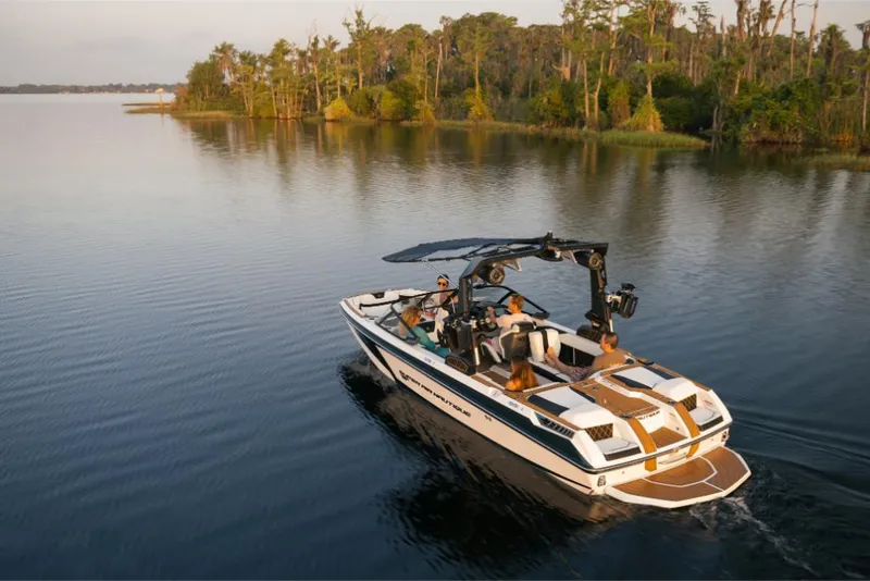 Slide: The Image of 2023 Nautique Super Air GS22E boat cruising on a serene lake. - 2