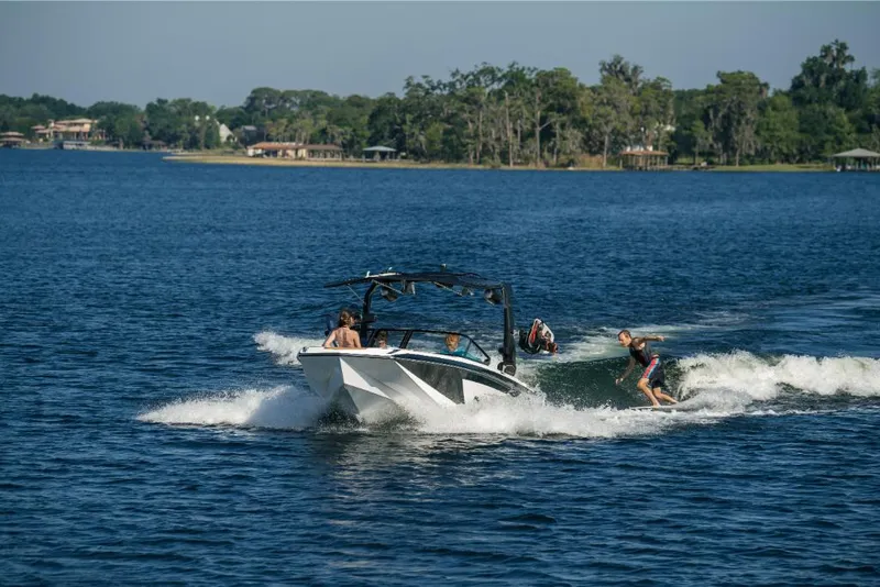 Slide: The Image of 2023 Nautique Super Air GS22E towing wakeboarder on a scenic lake. - 20