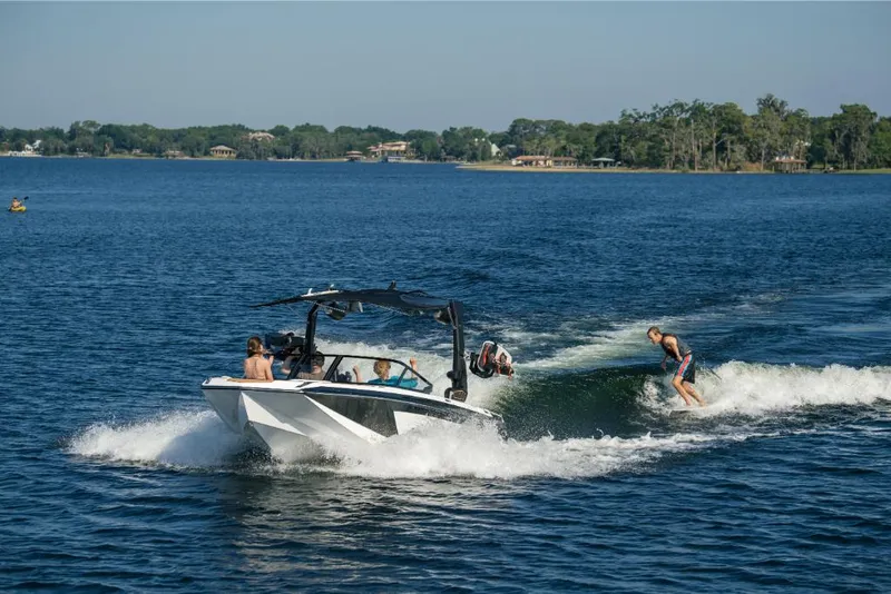 Slide: The Image of 2023 Nautique Super Air GS22E towing wakeboarders on a lake. - 21