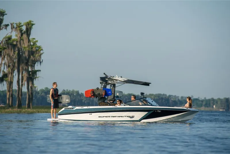 Slide: The Image of 2023 Nautique Super Air GS22E boat on a lake with people wakeboarding. - 28