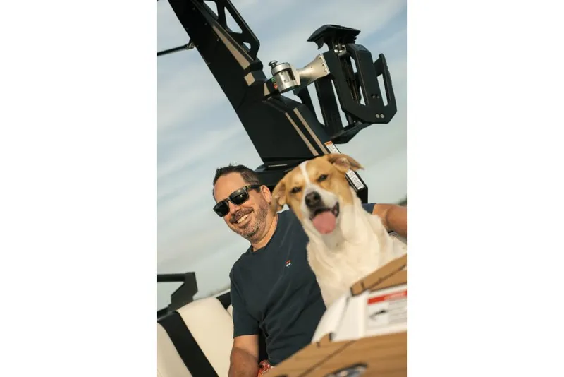 Slide: The Image of Man and dog enjoying a ride on a 2023 Nautique Super Air GS22E boat. - 31