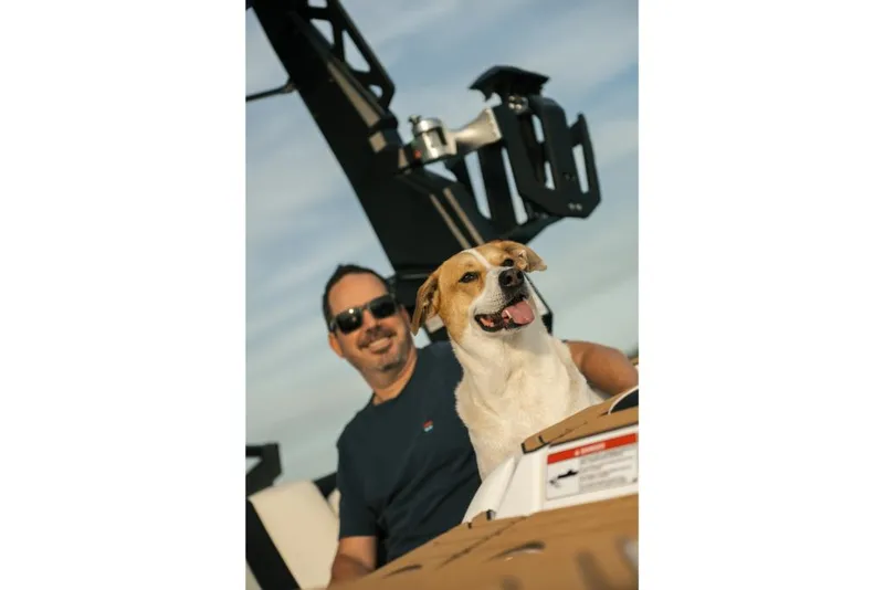Slide: The Image of Man and dog enjoying a ride on a 2023 Nautique Super Air GS22E boat. - 32