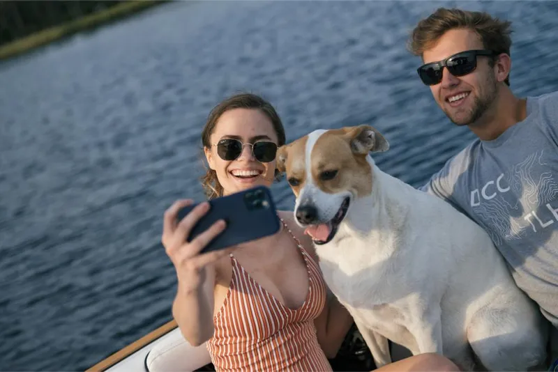 Slide: The Image of Couple and dog taking a selfie on a 2023 Nautique Super Air GS22E boat. - 36