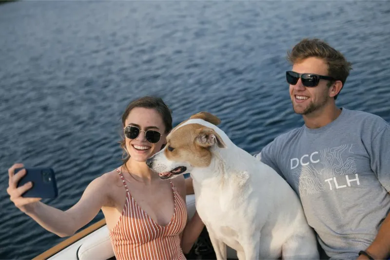 Slide: The Image of Couple and dog taking a selfie on a 2023 Nautique Super Air GS22E boat. - 37