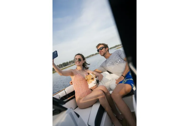 Slide: The Image of Couple and dog taking a selfie on a 2023 Nautique Super Air GS22E boat. - 39