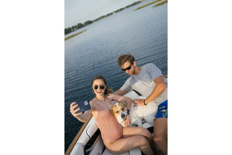 Slide: The Image of Couple and dog taking a selfie on a 2023 Nautique Super Air GS22E boat. - 40