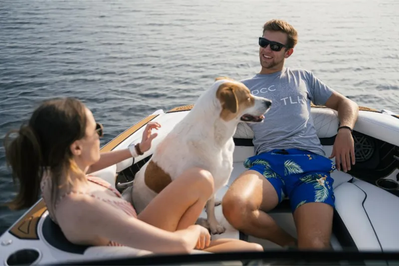Slide: The Image of Couple and dog relaxing on 2023 Nautique Super Air GS22E boat. - 44