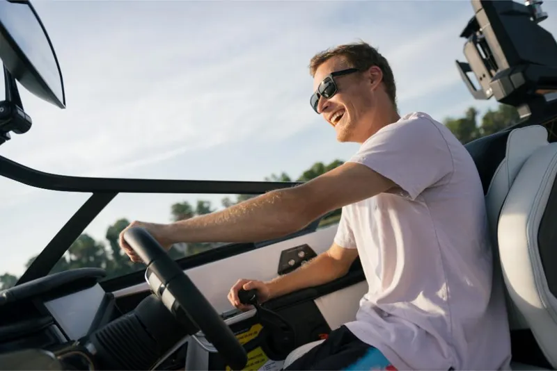 Slide: The Image of Man driving 2023 Nautique Super Air GS22E boat, smiling and wearing sunglasses. - 47
