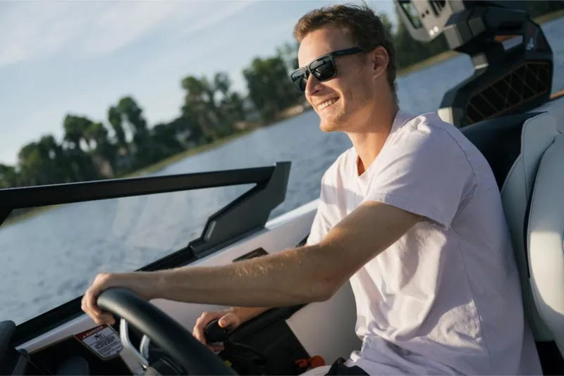 Slide: The Image of Man driving 2023 Nautique Super Air GS22E boat on a sunny day. - 49