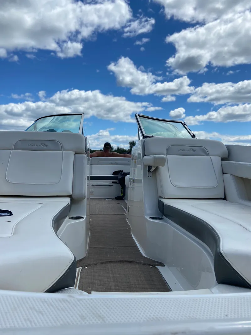Slide: The Image of 2012 Sea Ray 26 Bow Rider boat interior with white seating under a blue sky. - 9